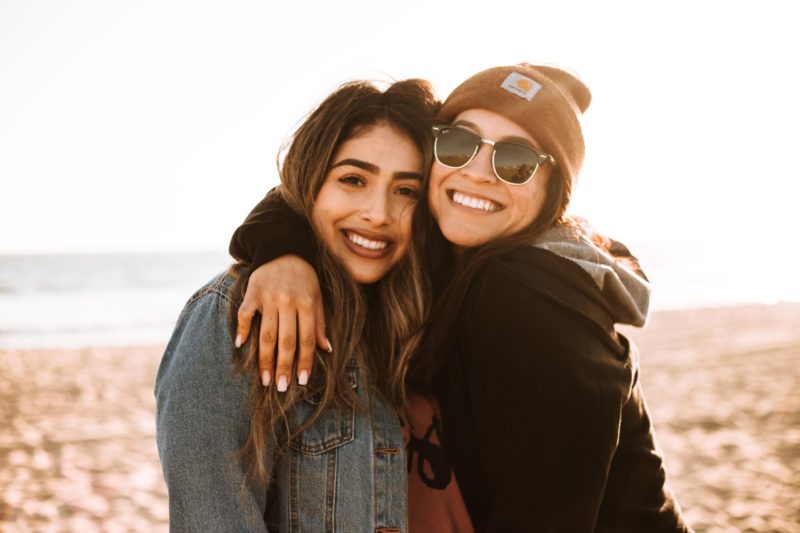 Two young women hug on a beach
