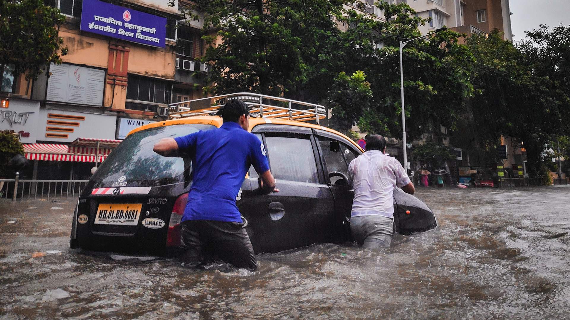 men pushing car through flood